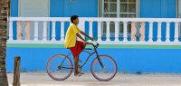 Junge auf Fahrrad vor blauem Haus in Belize